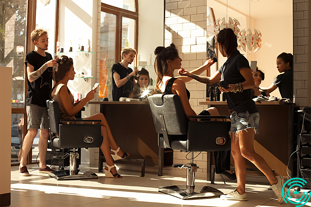 2 hairdressers (a man and a woman) in a salon with 2 female clients
